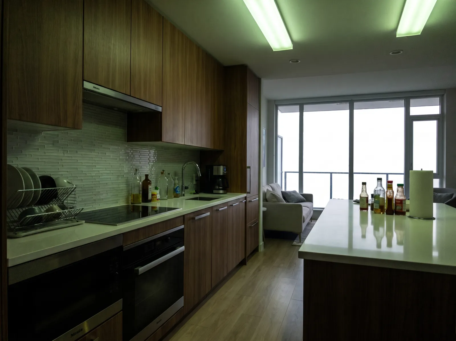 Condo galley kitchen straight off the phone: skyline blown out, green fluorescent cast